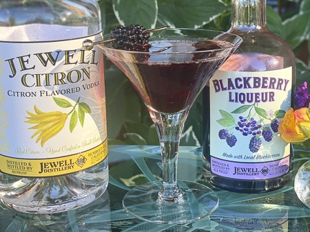 jewell citron bottle with a martinin glass with a blackberry cocktail garnished with blackberries